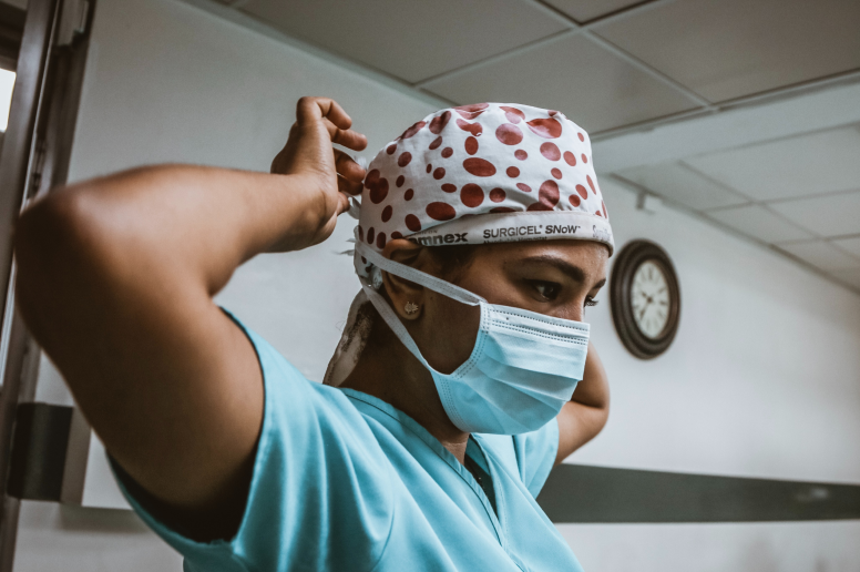 Person wearing scrubs and mask and red polka dotted hair bandana